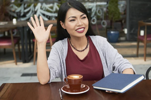 Glückliche Asiatische Frau Die Tisch Sitzt Kaffee Trinkt Und Winkt — Stockfoto