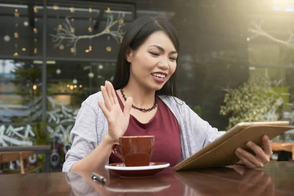 Sorridente Donna Asiatica Seduta Caffè Alla Tazza Caffè Agitando Qualcuno — Foto Stock