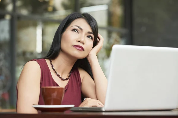 一杯のコーヒーでカフェに座って ノート パソコンの前で新しいアイデアを考えるアジアの実業家 — ストック写真