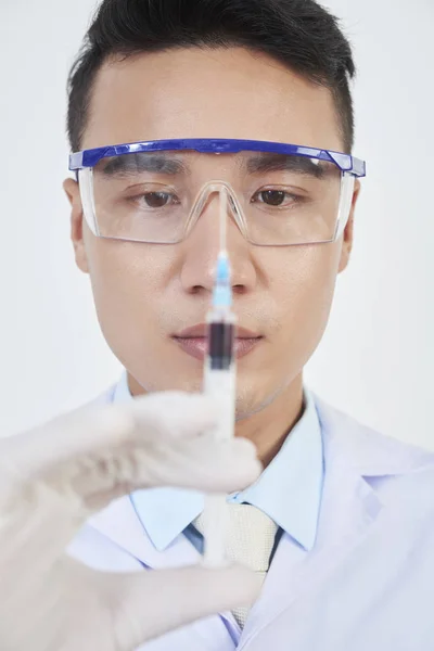 Junger Vietnamesischer Arzt Mit Schutzbrille Blickt Auf Spritze Seinen Händen — Stockfoto