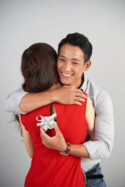 愉快英俊的年轻人拥抱他的女朋友在接受小情人节礼物以后 — 图库照片