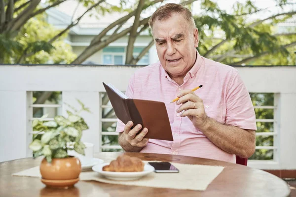 Seriöser Senior Überprüft Seine Notizen Planer — Stockfoto