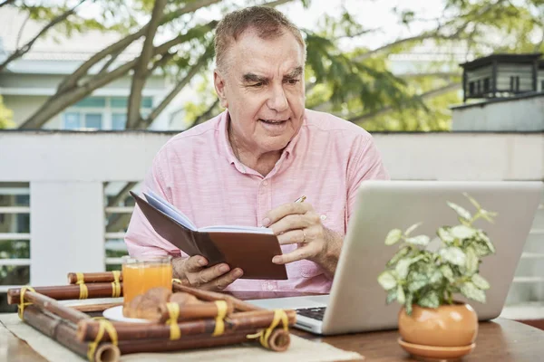 Starší Muž Který Sledoval Laptop Pořizování Poznámek Učebnici — Stock fotografie
