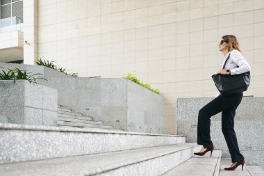 Merdivenlerden yukarı yürümek büyük çanta ile şık iş kadını