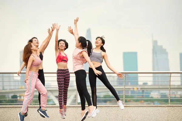 Group Laughing Asian Woman Sportswear Jumping Giving High Five Cityscape — Stock Photo, Image