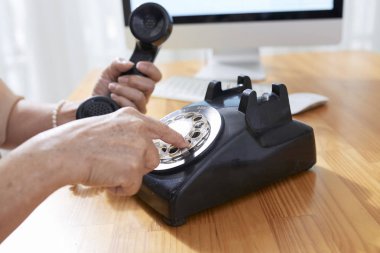 Eski telefon telefon numarasını çevirirken kullanan yaşlı kadın