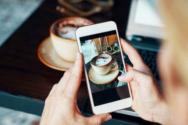 Erkek Close-Up holding cep telefonu eller. Kafede masada kahve fincan fotoğrafın yapma kadın