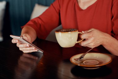 Onun akıllı telefon üzerinde kahve ve manifatura iletiyle kafede oturan kadın Close-Up