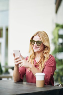 Kahve içme ve kafe mekanlarda dinlenirken smartphone kullanarak güzel kadın