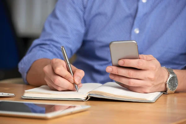 Manos Hombre Negocios Comprobando Teléfono Inteligente Tomando Notas Libro Texto — Foto de Stock