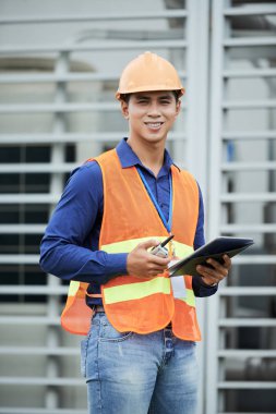Asya yakışıklı tablet ve telsiz telefon tutarak yelek ve kask 