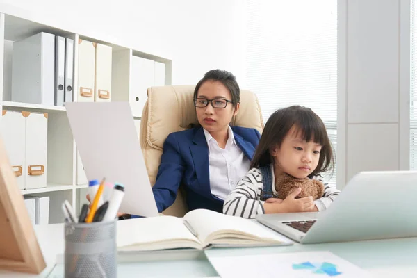 アジアの女性の魅力的な小さな娘と事務所で作業しながらドキュメントを読んでスーツ — ストック写真