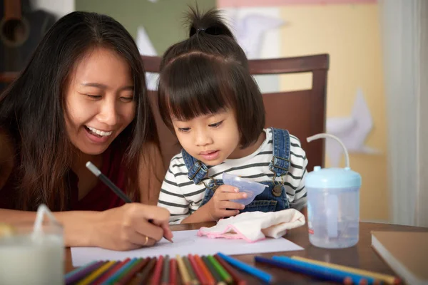 亚洲成年妇女坐在桌子上 带着小女儿一起在纸上画画 用彩色铅笔玩得很开心 — 图库照片