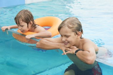 Neşeli kardeşler yüzme havuzunda aqua park zevk