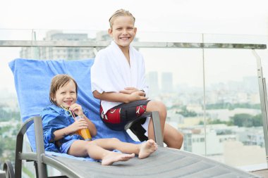 Mutlu çocuk Yüzme Havuzu sonra sıcak havlu, şezlong üzerinde oturan