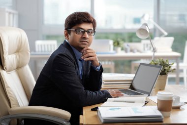 Onun office masada oturan ve kameraya bakarak ciddi Hint girişimci