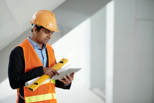印度工程师与建筑水平阅读信息在平板电脑上 — 图库照片