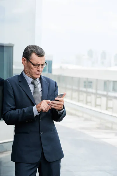 Ernstige Ondernemer Leunend Muur Het Controleren Van Berichten Smartphone — Stockfoto