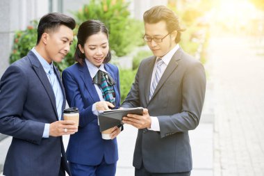 Modern genç Asyalı işkadını Caddesi üzerinde kahve ile tablet birlikte ayakta kullanarak arkadaşlarınızla 