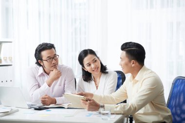 Zarif modern Asya kadın ve tablet ile coworking ve konuşmaya ofis masada oturan adam