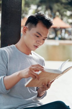 Yakışıklı Asya'ya ait adam zaman sokakta güneşli günde harcama ise ilginç bir kitap okuma