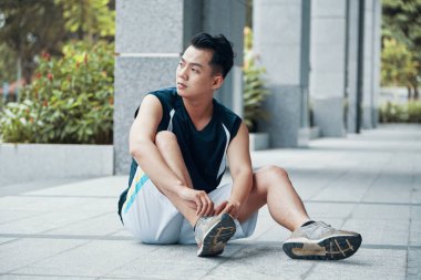 Dantel spor ayakkabılar üzerinde bağlıyor ve uzak yere açık eğitim sırasında otururken seyir spor giyim çekici Asya'ya ait adam