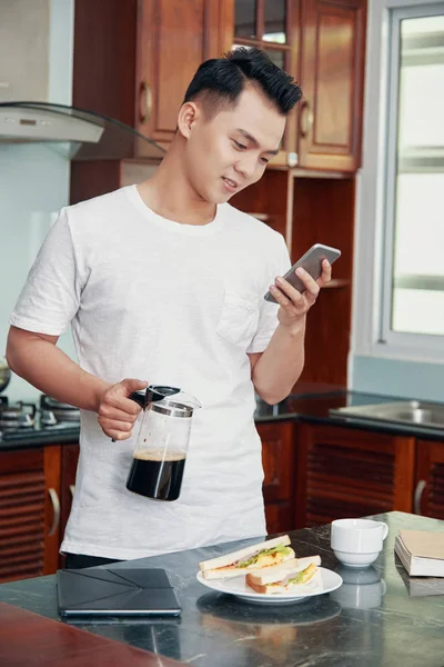 Sürahi Kahve Ile Tutarak Evde Mutfak Smartphone Kullanarak Rahat Asyalı — Stok fotoğraf