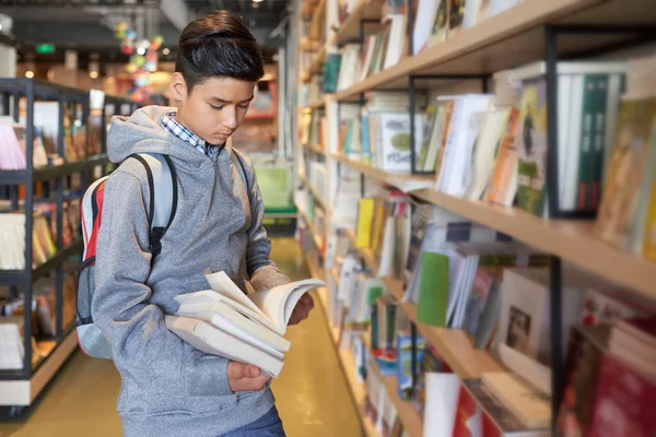 Schuljunge Steht Mit Büchern Arm Und Blättert Konzentriert Durch — Stockfoto
