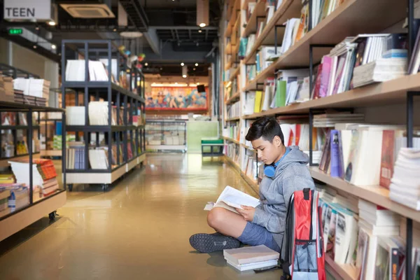 Sidovy Tonårspojke Med Hörlurar Som Sitter Biblioteket Golvet Med Ryggsäck — Stockfoto