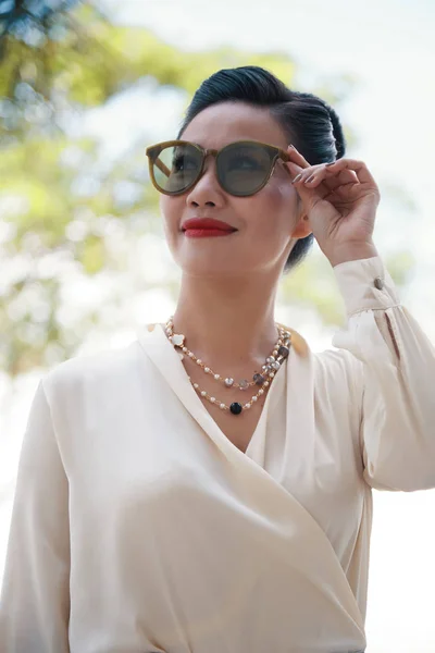 Beautiful Cheerful Asian Woman Delicate Blouse Necklace Touching Trendy Sunglasses — Stock Photo, Image