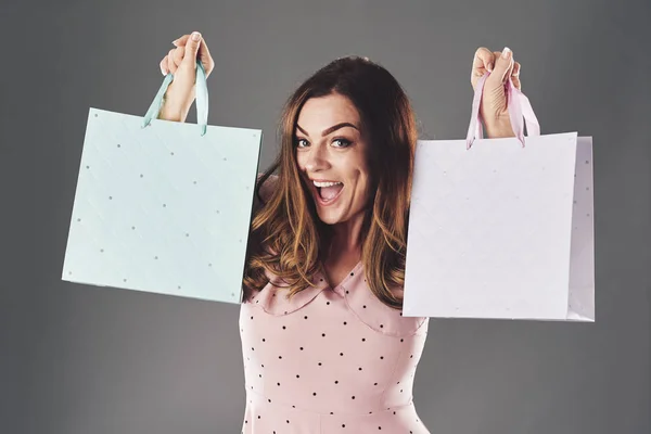 Lovely cheerful woman raising hands with shopping bags