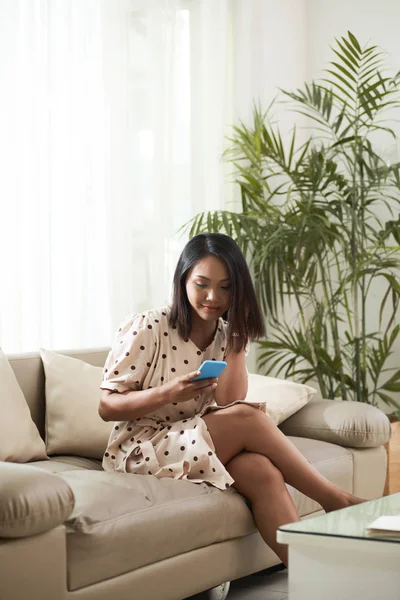 Glada Asiatisk Kvinna Sitter Soffan Och Kontrollera Sin Smartphone — Stockfoto