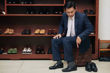 Middle-aged Vietnamese man trying on black shoes clipart