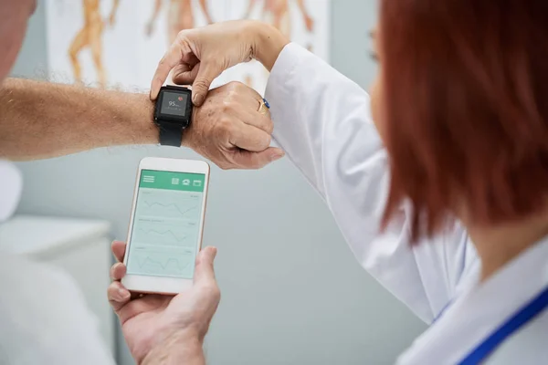Lekarz Wyświetlono Starszy Pacjent Sposobu Synchronizowania Aplikacji Zdrowie Smartfonie Smartwatch — Zdjęcie stockowe