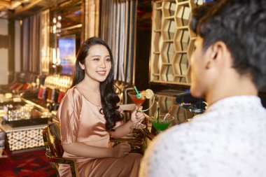 Kokteyl tutarak ve restaurant sevgilisi ile romantik bir tarih yaparken gülümseyen güzel Asyalı kadın