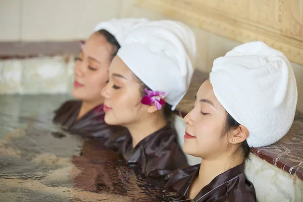目を閉じ リラックスした水に座っている 頭にタオルで若いアジアの女の子のグループ — ストック写真