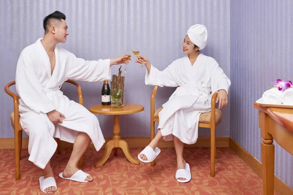 Junges Lächelndes Paar Das Bademänteln Sitzt Und Champagner Trinkt Während — Stockfoto