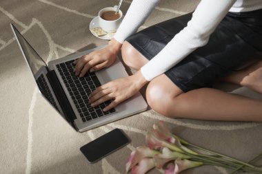 Katta oturan ve dizüstü bilgisayarda çalışan kadın Blogger Resim kırpılmış