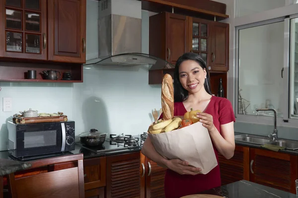 新鮮な食料品が詰まった紙パッケージを保持している魅力的な笑みを浮かべてアジア女性 — ストック写真