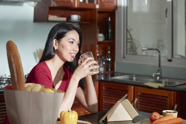 Jonge Lachende Vietnamese Vrouw Zitten Keuken Glas Water Drinken Alvorens — Stockfoto