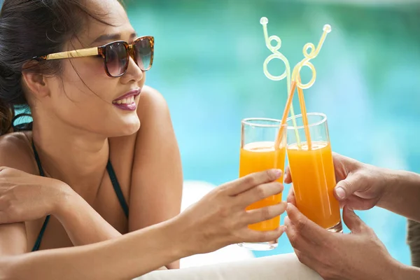 在户外日光浴时 戴着太阳镜和男朋友一起用新鲜的橙汁敬酒的年轻女子 — 图库照片