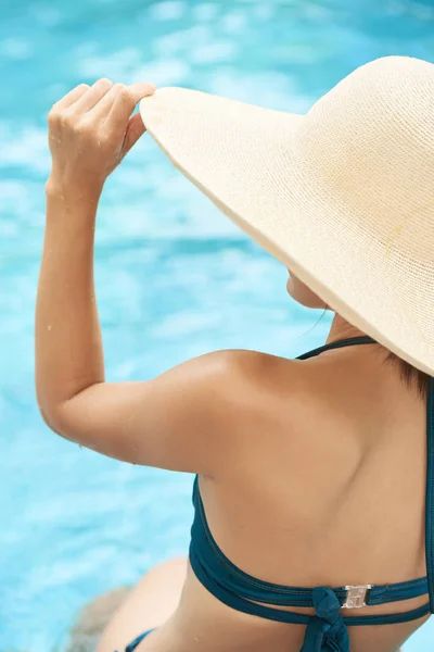 暑假期间 年轻漂亮女孩戴着沙滩帽 坐在游泳池附近的后景 — 图库照片