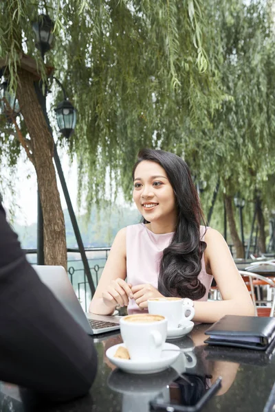 Young Asian female entrepreneur meeting with client in outdoor cafe