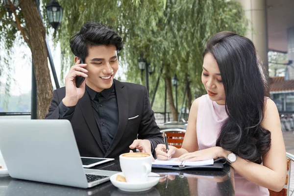 ノート パソコンと携帯電話とのテーブルで若いアジア ビジネス パートナー — ストック写真