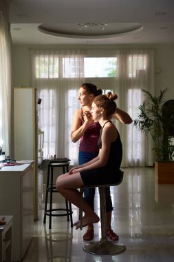 Süre o Güzellik Salonu sandalye üzerinde oturan genç kadın için makyaj yapıyor profesyonel makyaj sanatçısı