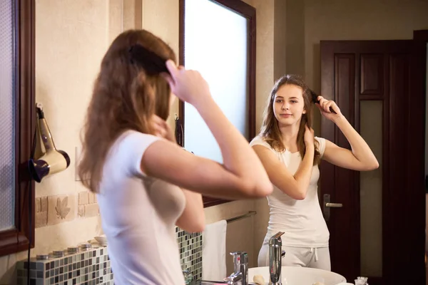Menina Olhando Para Espelho Escovando Seu Cabelo Longo Com Escova — Fotografia de Stock