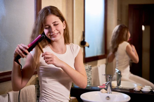 Sorrindo Jovem Mulher Fazendo Estilo Usando Alisador Cabelo Frente Espelho — Fotografia de Stock