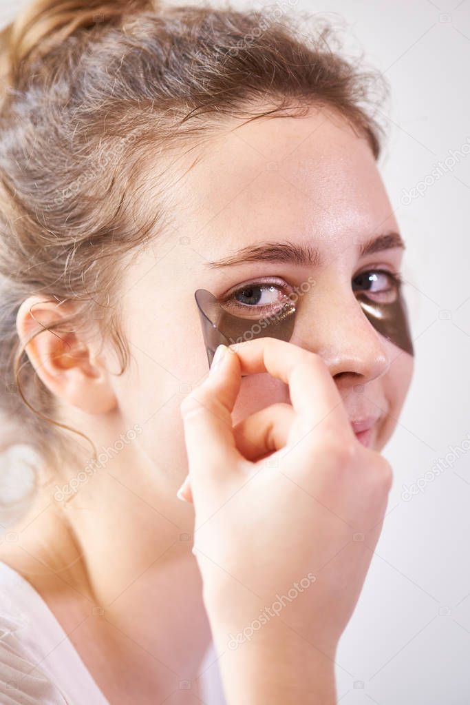 Close-up of young woman applying eye patches on her face for skin beauty