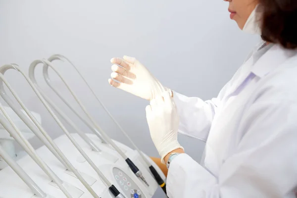 白いガウンを歯科医院でクライアントでの作業の前に手袋に置くことの女性の側面ビューのトリミング — ストック写真