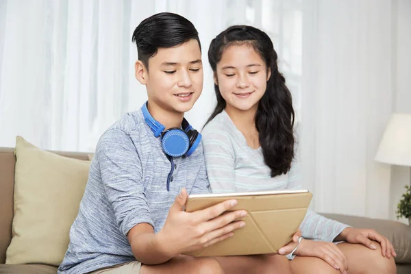 微笑的十几岁双胞胎在数字平板电脑上观看音乐视频 — 图库照片